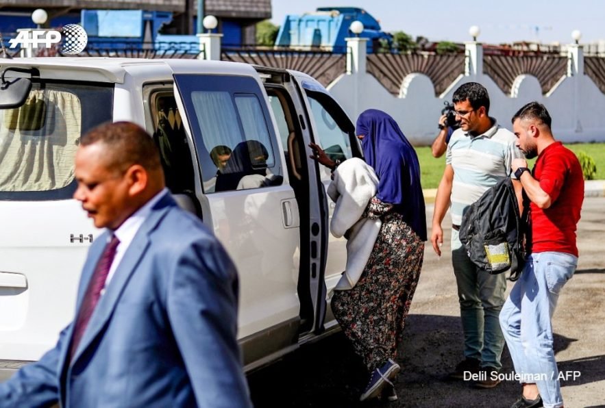 امرأة سودانية تحمل طفلاً عمره شهر واحد ، متهمة بالانضمام إلى جماعة داعش الإرهابية ، يرافقها دبلوماسي سوداني في مدينة القامشلي شمال شرق سوريا ، بعد أن سلمتها السلطات الكردية يوم الخميس ل( ا ف ب)