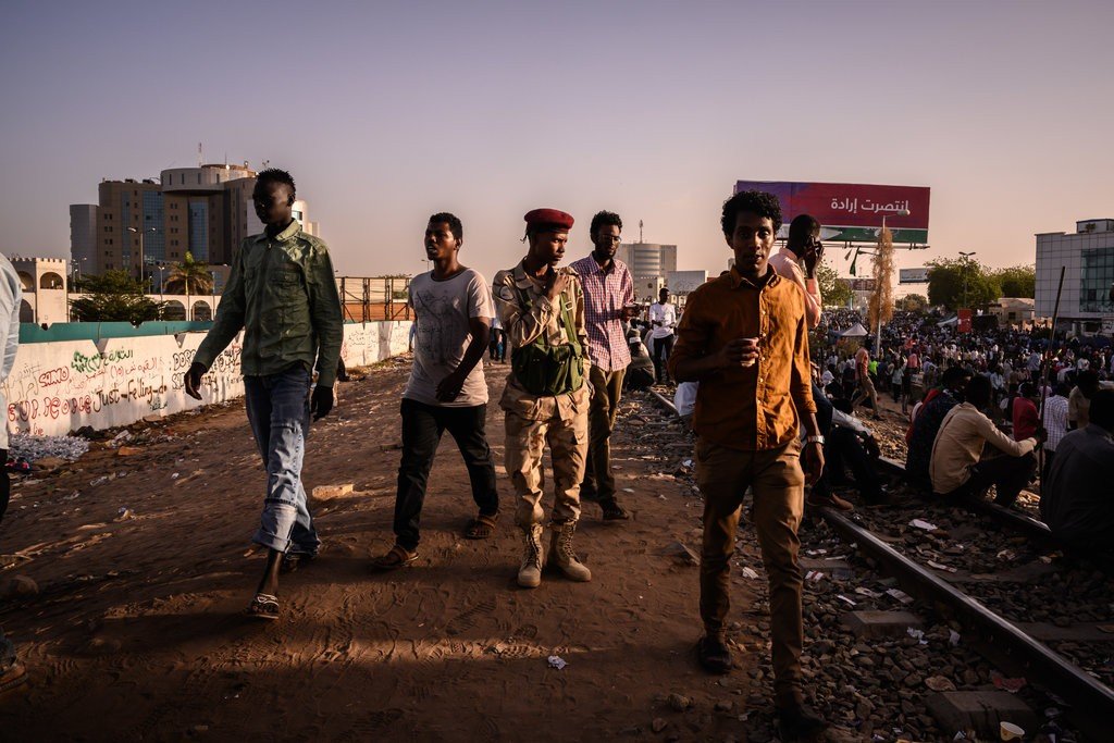 متظاهرون وجندي سوداني خارج القيادة العامة للجيش السوداني في الخرطوم . صورة ل(نيويورك تايمز)